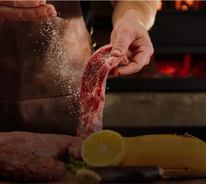 Homem temperando uma peça de carne para churrasco.